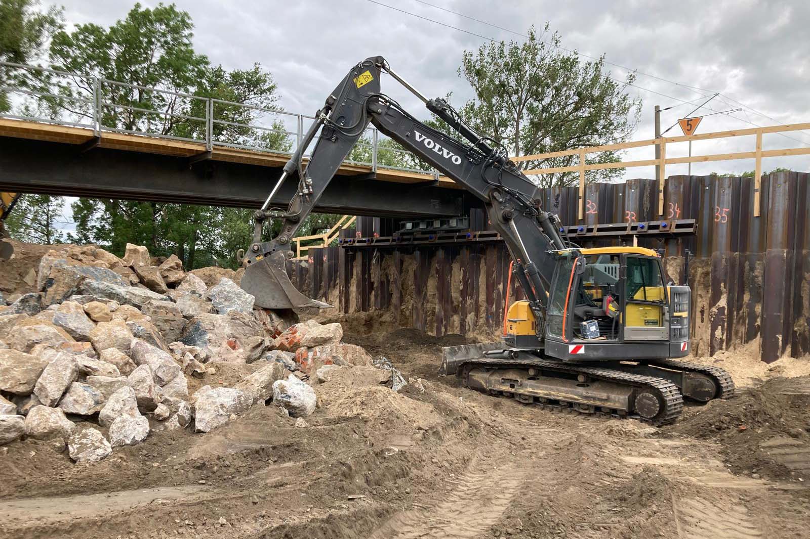 Bau eines Gleises unter einer Brücke, Freiräumung durch Bagger